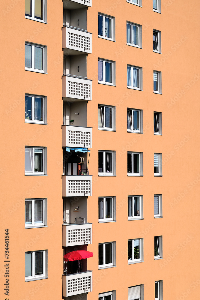 Colorful apartment block facade with one single isolated red umbrella on a balcony.
