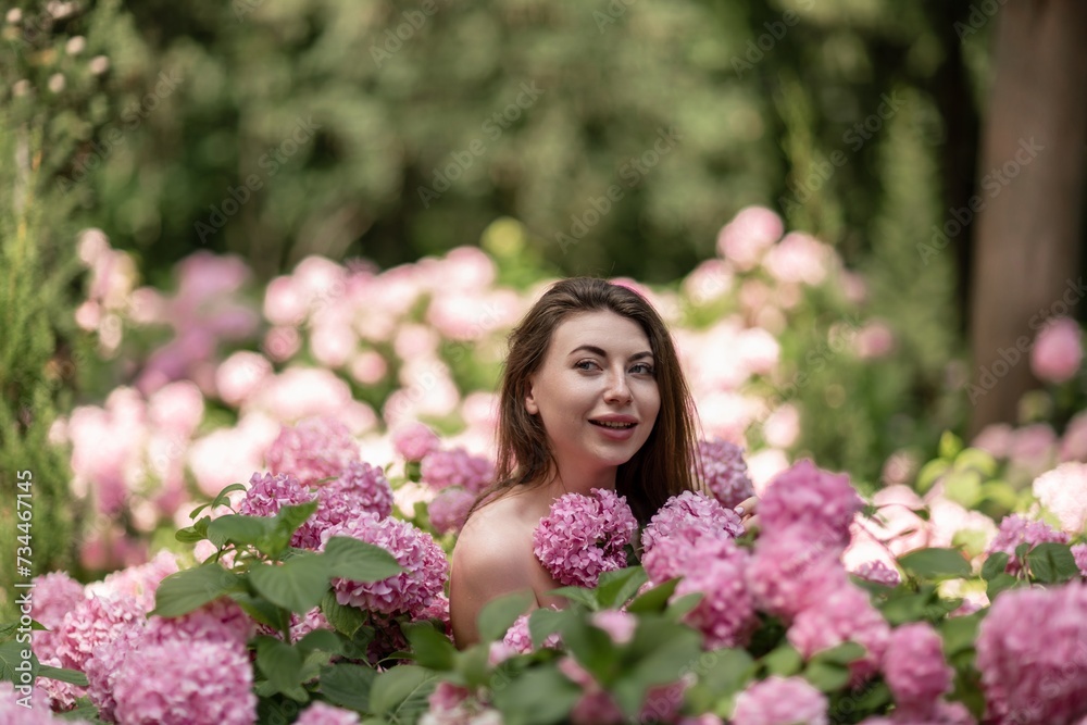 Hydrangeas Happy woman in pink dress amid hydrangeas. Large pink hydrangea caps surround woman. Sunny outdoor setting. Showcasing happy woman amid hydrangea bloom. Hydrangeas Happy woman in pink dress amid hydrangeas. Large pink hydrangea caps surround woman. Sunny outdoor setting. Showcasing happy woman amid hydrangea bloom.