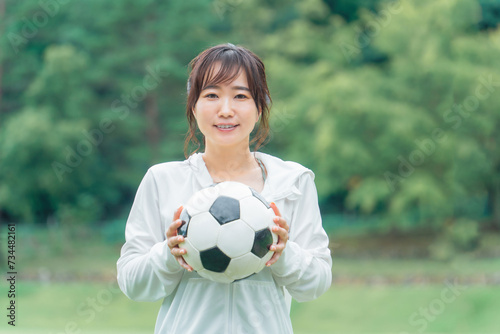 運動場でサッカーボールを持つサッカーファン・サポーターの日本人女性  © buritora