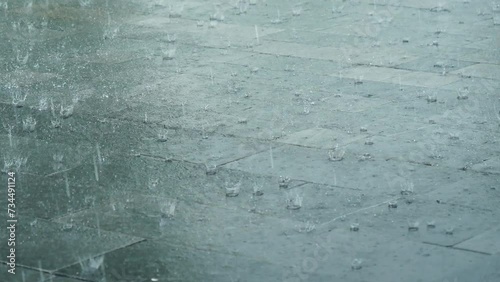 Heavy rainy in raining season weather during thunderstorm raindrops splash on water surface. Blurred background while falling rain shower windy outdoors. Climate change motion raindrops splash photo
