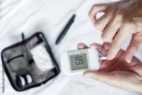 Closeup of people performing routine blood sugar monitoring with glucometer at home.