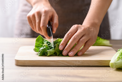 Organic cos romaine lettuce cutting on wooden board, Food ingredient for healthy salad photo