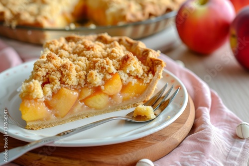 Close up selective focus of homemade apple peach shortcrust pie with crumble on wooden board and pink napkin served with a fork saucer and fresh fruits photo