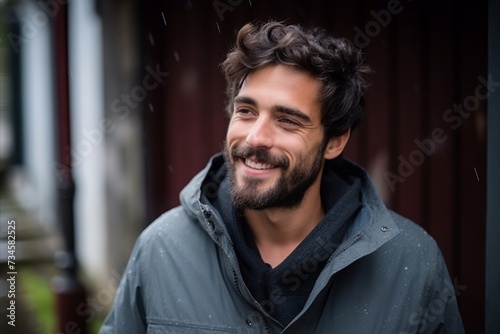 Portrait of a handsome young man smiling at the camera in the rain