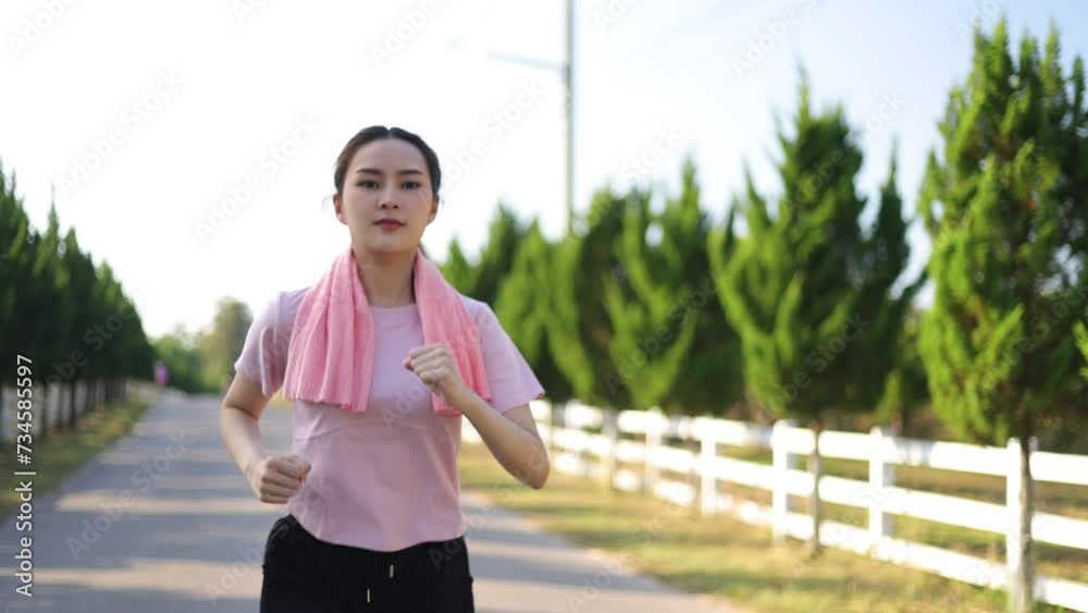 Young beautiful Asian woman with good health is jogging on the road in the park. Young beautiful Asian woman with good health is jogging on the road in the park.