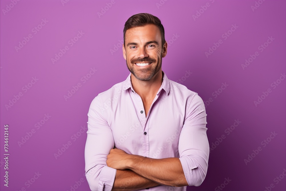 Portrait of a smiling young man standing with arms crossed against purple background