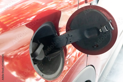 Close up view of the fuel tank cap cover on the red car. Open petrol cap cover.