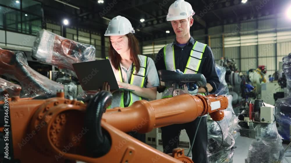 Male and female electrician robot engineer inspecting new welding robot testing electrical installation process with laptop electronic automation system setup in warehouse modern business industry 4.0 Male and female electrician robot engineer inspecting new welding robot testing electrical installation process with laptop electronic automation system setup in warehouse modern business industry 4.0
