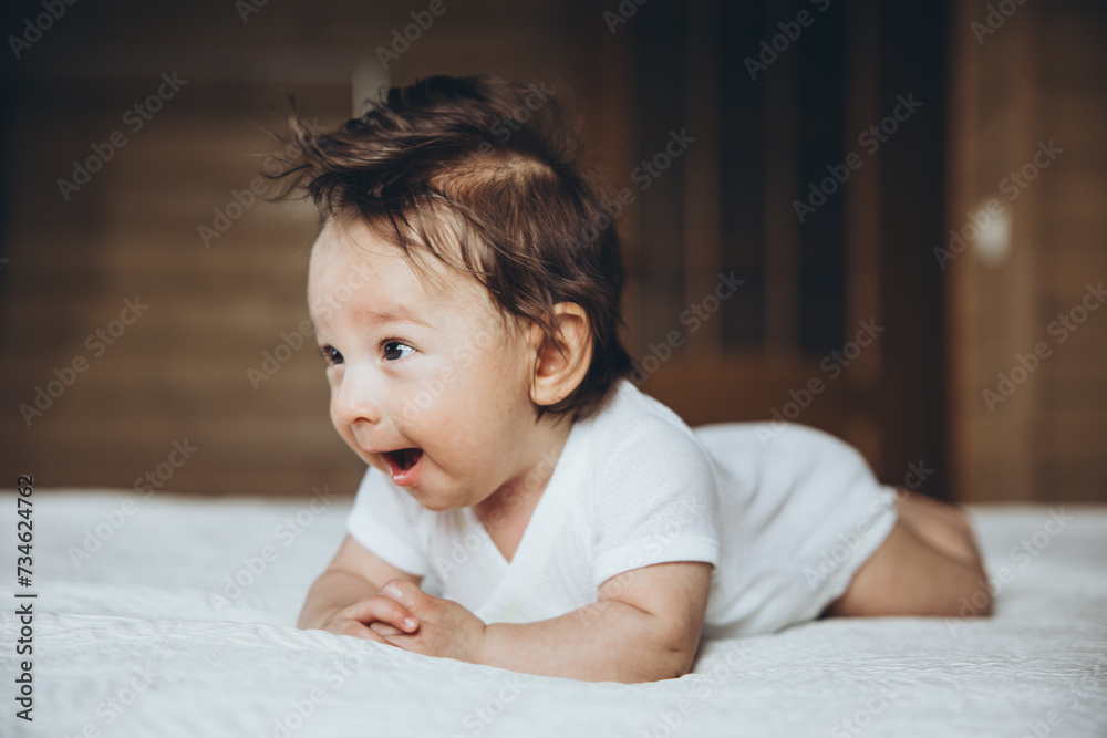 Smiling newborn boy with long braun hair is laying on the bed Smiling newborn boy with long braun hair is laying on the bed
