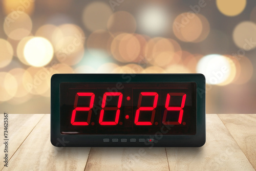 number 2024 on electric clock screen on desk with blur colorful cosy light bokeh, time signs for beginning or end of the year