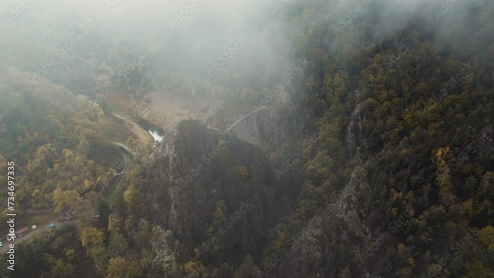 drone shot revealing gouffre d'enfer dam near saint etienne on a moody day with fog and low clouds, fance