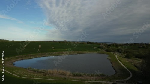 Footage of a lake by a field, recorded by a drone flying over the lake. photo