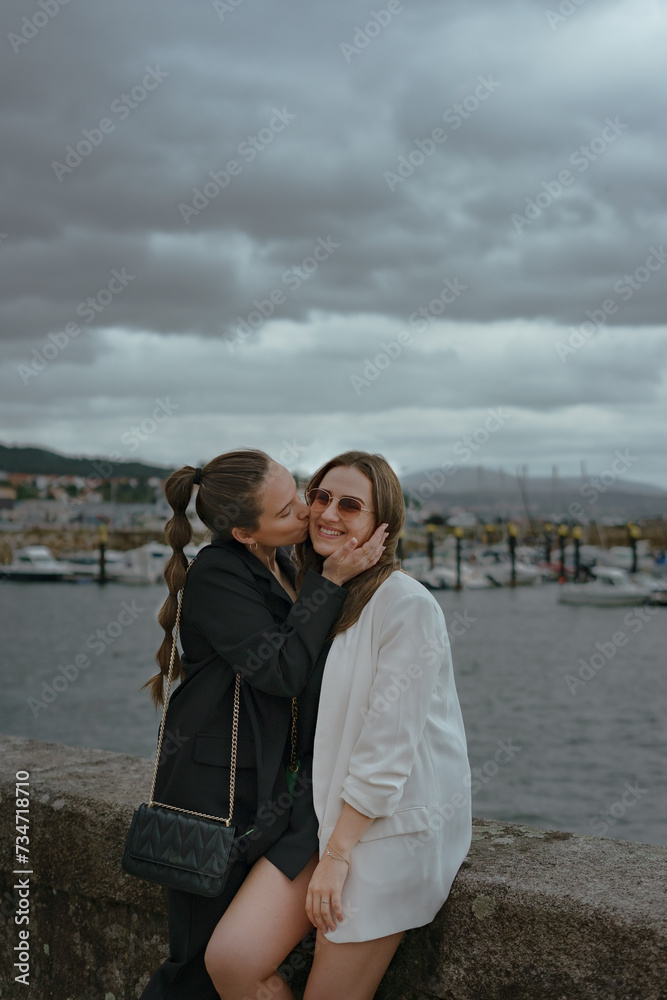 Young woman kissing her sister in the harbour.