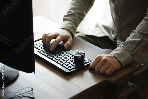 A man with a gift in his hand sits in front of the monitor screen. Order a gift for home and office.