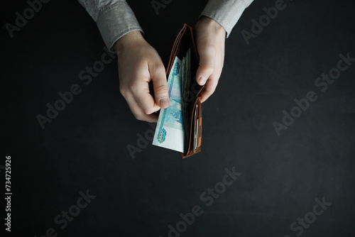 Hands take out cash banknotes from a wallet on a gray background. Foreign currency. photo
