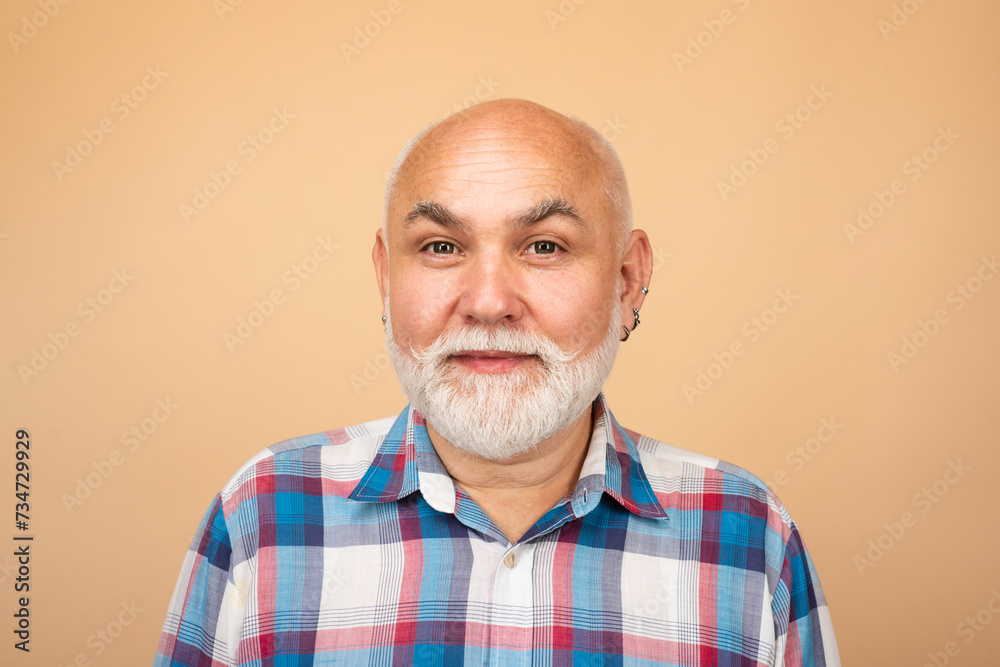 Obraz premium Close-up studio portrait of senior man looking at camera. Golden age grandfather. Bearded old aged man, head and shoulders portrait.
