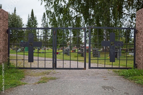 Entrance to cemetery with old wrought iron gate with crosses.