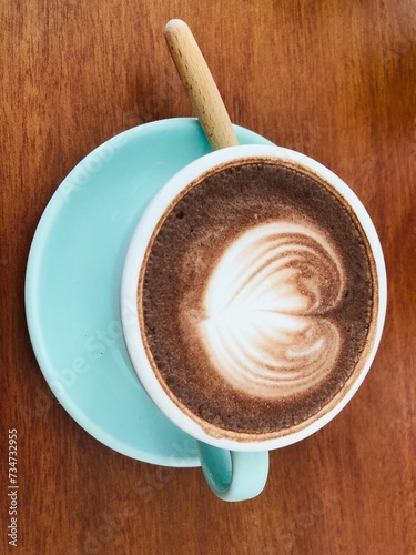 Close up shot of hot latte coffee with latte art in a ceramic white cup and saucer on white background with clipping path. Hot milk art coffee on a wooden table, A cup of hot coffee with latte art on.