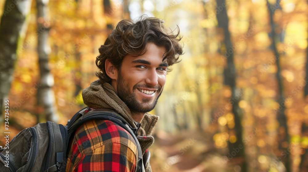 Picture of man with backpack smiling while surrounded by trees in woods. Suitable for outdoor adventure, hiking, and travel-related themes