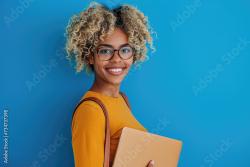 Woman with curly hair and glasses holding laptop. Perfect for illustrating technology, remote work, or online communication