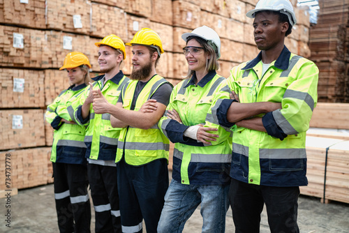 Group of people team wear safety helmet and uniform standing in factory. Engineer men and women colleague in hardhat working together in pallet manufacturing warehouse. teamwork. Young adult workers.