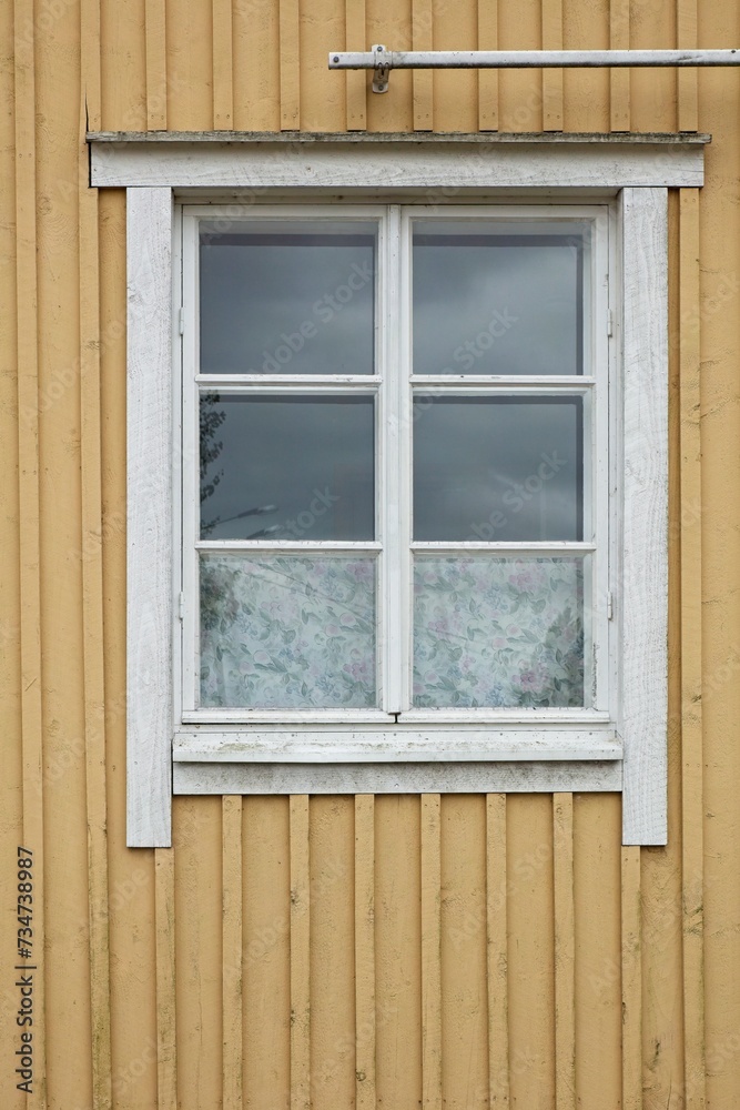 White framed window on yellow painted wooden wall.