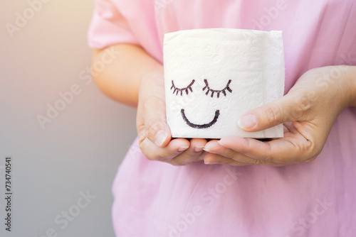 Cropped image hands of women holding a white toilet paper with smiley face. photo