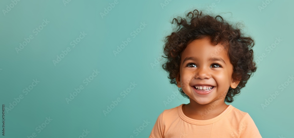 Close view of a charming 3-year-old Indian toddler, displaying innocence and happiness on a pastel solid-colored background