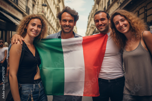 four friends taking a photo holding the flag of Italy in the streets of a big city