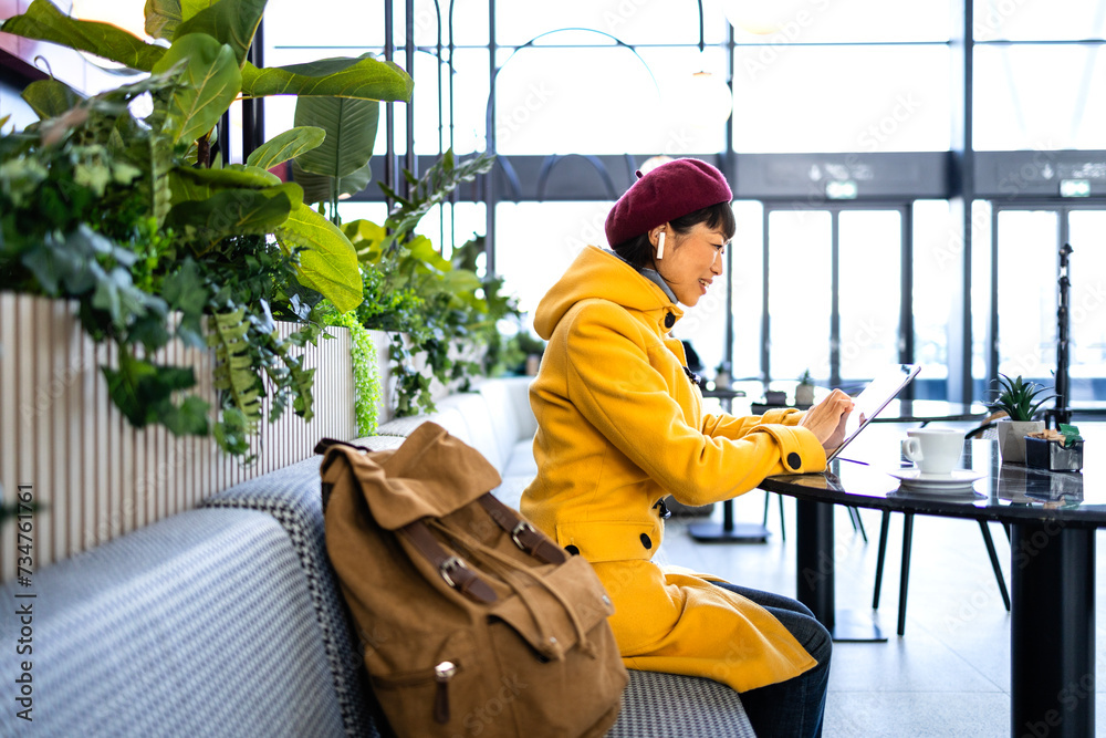 Female passenger with backpack sitting in airport cafe bar waiting for the flight.