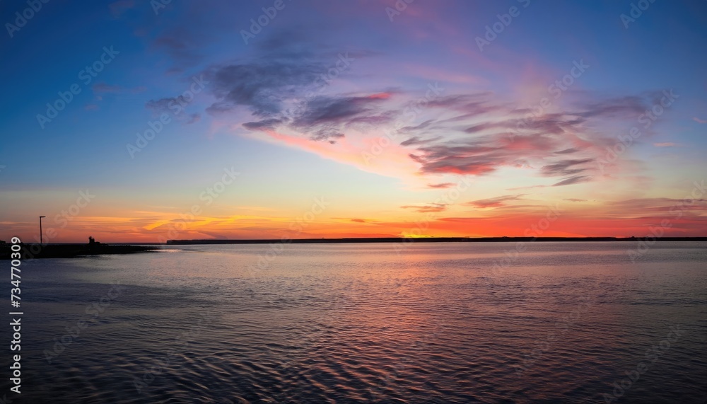 A wide-angle image of the sunset beyond the bay in Delaware showing dynamic red, orange, and blue colors