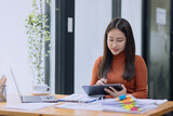 Happy asian accounting businesswoman working with tablet in office working space, Asian female employee using laptop at workplace.