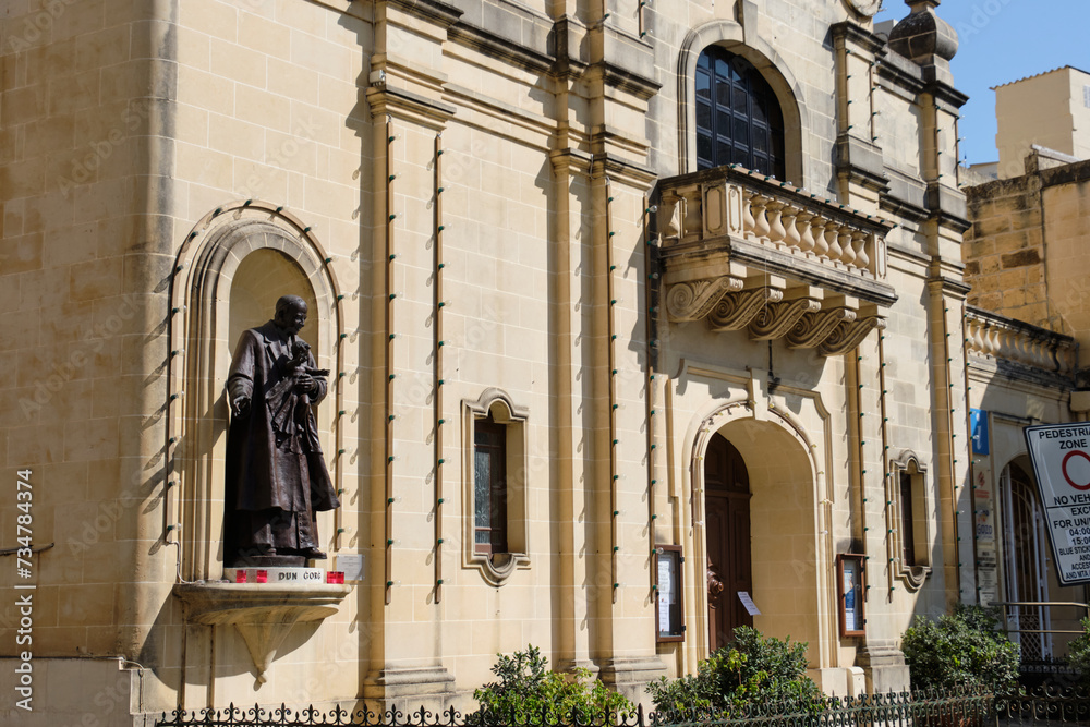 The life-size bronze statue of San George Preca, the founder of the Society of Christian Doctrine as well as a Third Order Carmelite, on the façade of St James Church - Victoria, Malta