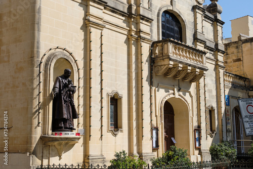 The life-size bronze statue of San George Preca, the founder of the Society of Christian Doctrine as well as a Third Order Carmelite, on the façade of St James Church - Victoria, Malta photo