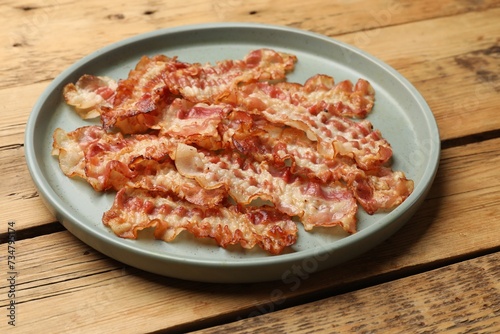 Delicious fried bacon slices on wooden table
