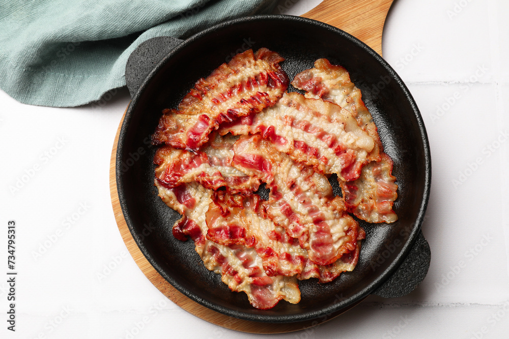 Delicious bacon slices in frying pan on white table, top view Delicious bacon slices in frying pan on white table, top view