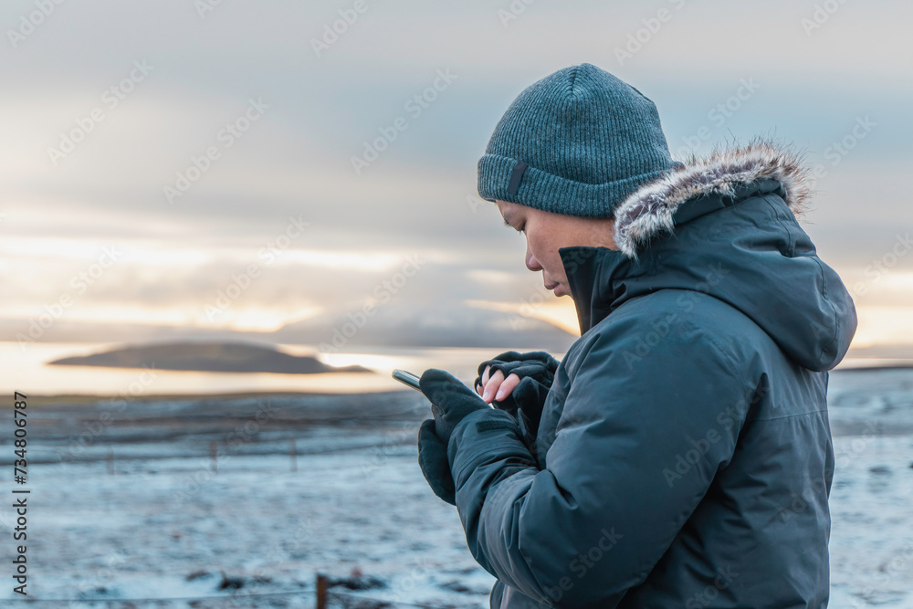 man in warm jacket using smartphone at twilight