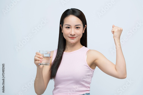 Asian woman drinking glass of water screaming proud, celebrating victory with raised arm