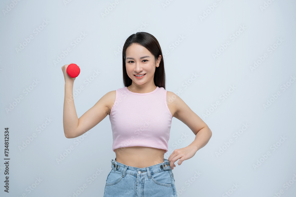 Happy motivated woman healthy weight loss lifting dumbbells in oversized jeans unwearable