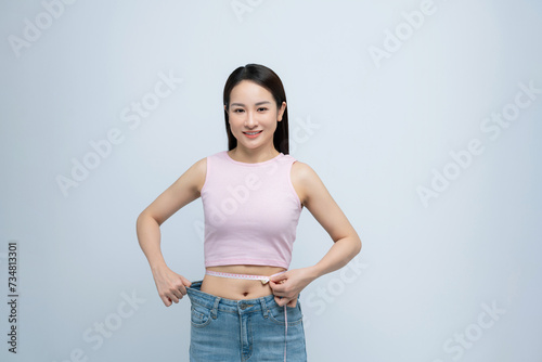Young fun woman show loose pants after weightloss hold measure tape on waist