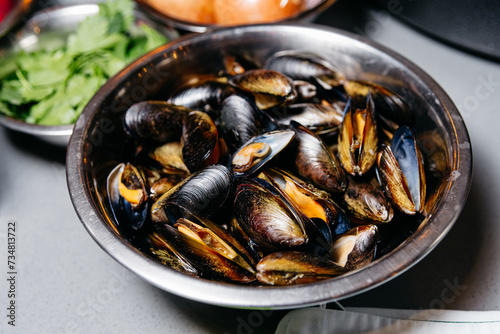 Fresh Mussels in Water in Metal Bowl. Fresh mussels soaked in water in a metal bowl, ready for cleaning and cooking in a kitchen setting.