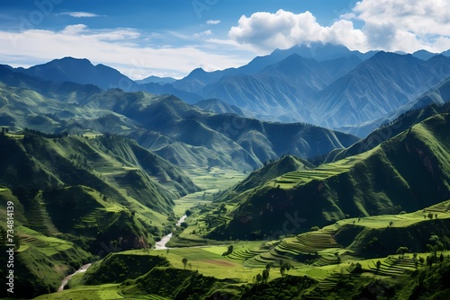 A panoramic view of undulating hills covered in vibrant greenery, merging into a towering mountain backdrop. photo