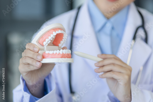 Asian female doctor dentist holding brackets and aligner at clinic.