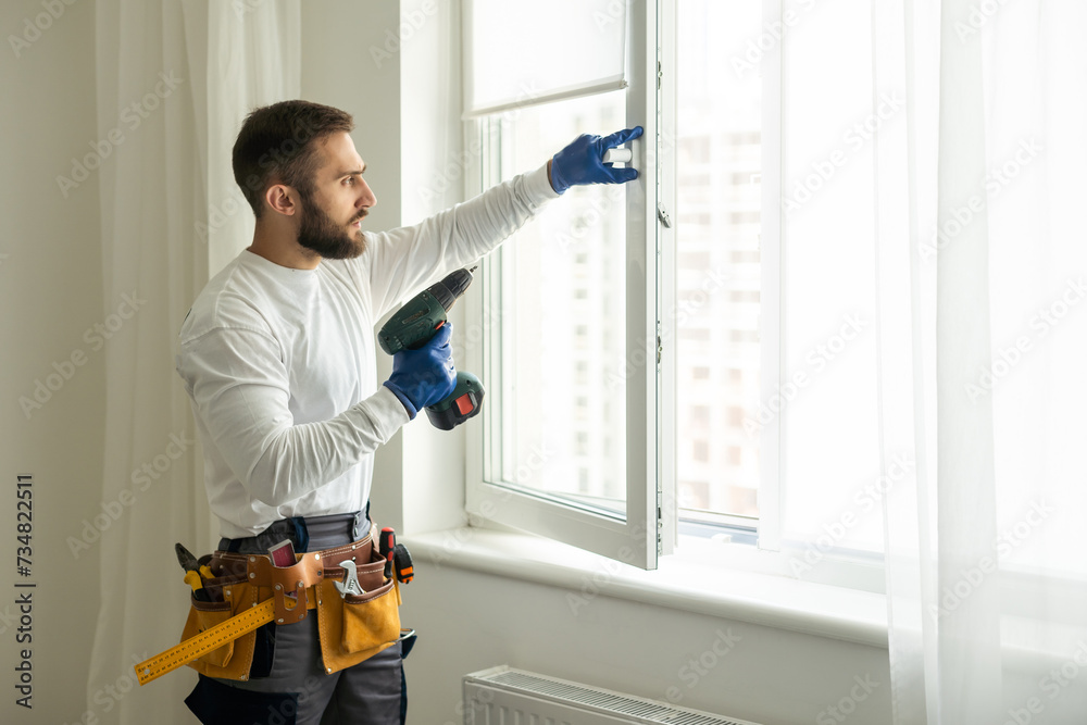service man installing window with screwdriver service man installing window with screwdriver