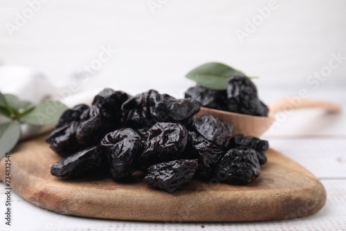 Tasty dried prunes on light wooden table, closeup