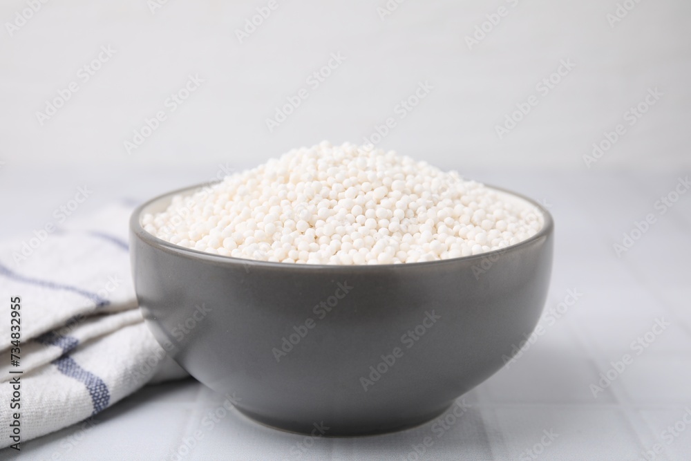 Tapioca pearls in bowl and towel on white tiled table Tapioca pearls in bowl and towel on white tiled table
