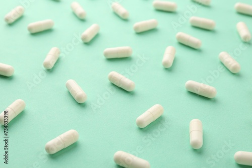 Many vitamin capsules on turquoise background, closeup