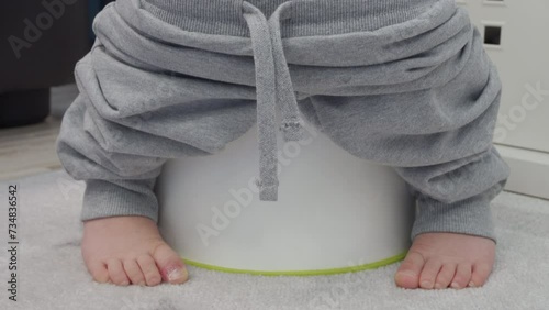 bare feet of child little boy sitting on a potty closeup photo