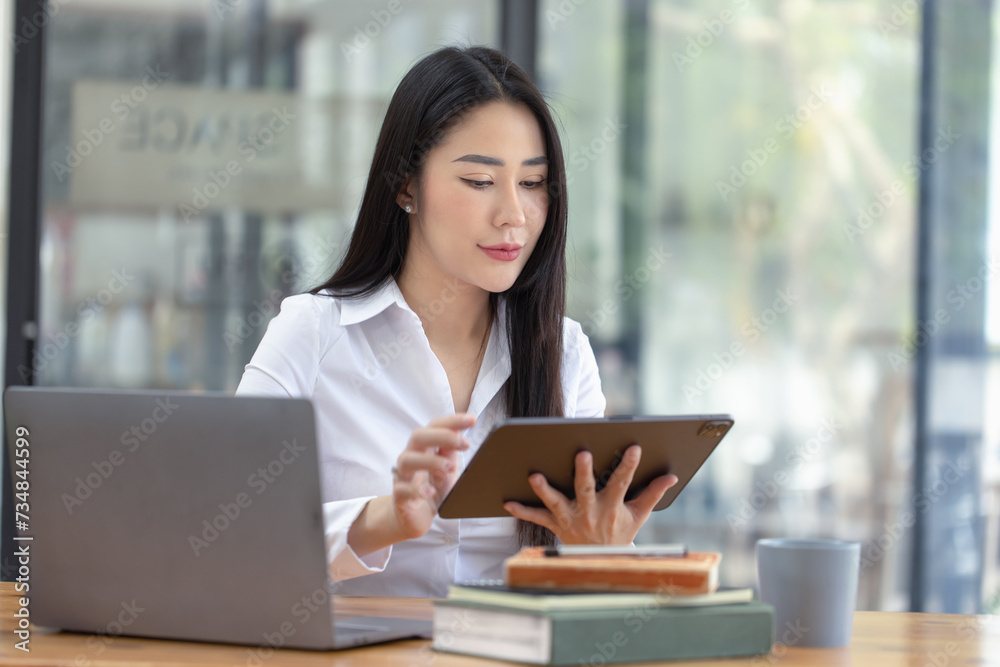 Happy asian young businesswoman using digital tablet sitting in office working space. Happy asian young businesswoman using digital tablet sitting in office working space.