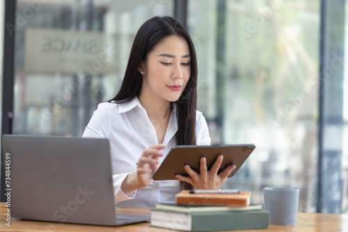 Free Download Happy asian young businesswoman using digital tablet  sitting in office working space. - GFXLoad